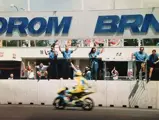 Having just crossed the finish line, Rossi’s teammates cheer from the paddock to celebrate the rookie’s first victory at the 1996 Czech Grand Prix.
