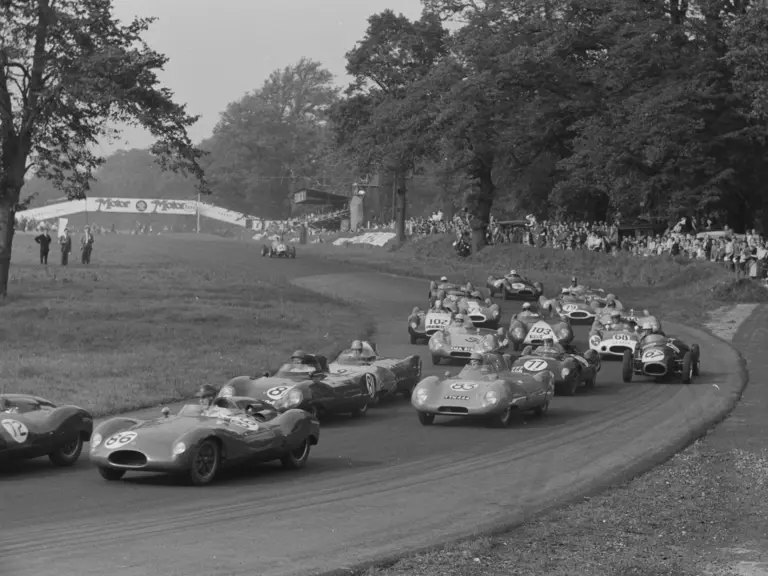 The Lotus (numbered 97) is pictured in a busy field at the Gold Cup Formula Two race at Oulton Park in 1956.