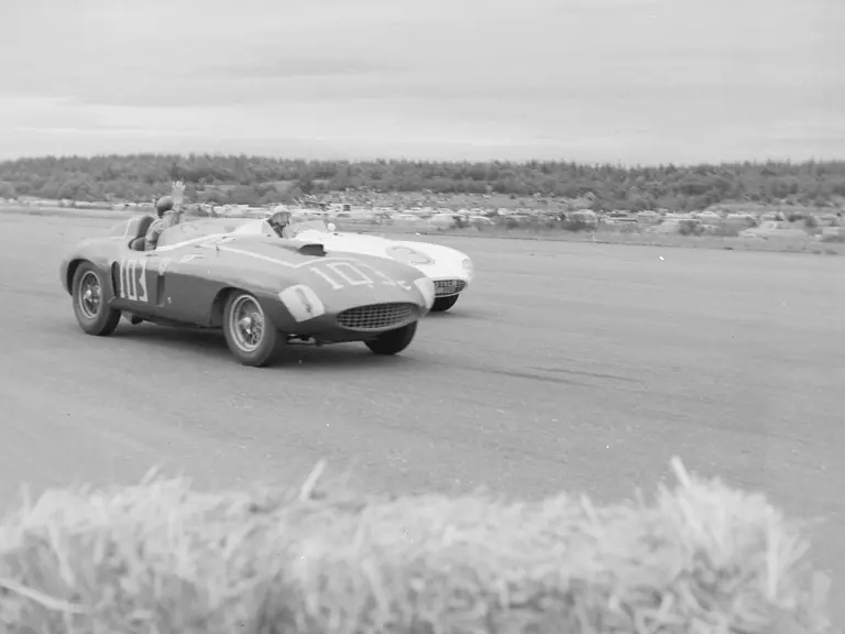 Carroll Shelby, behind the wheel of chassis no. 0478 AM (#103), gives a friendly wave to Phil Hill and his 750 Monza (#3) after beating him in the feature race at the 31 July 1955 SCCA Nationals held at Bremerton, Washington.