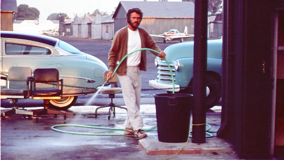 Steve McQueen with his 1952 Hudson Wasp proudly parked outside his hanger at the Santa Paula airport.