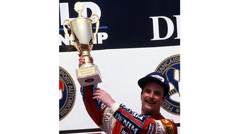 Nigel Mansell is triumphant at Circuit Paul Ricard as he holds aloft the 1st-place trophy from the 1987 French Grand Prix.