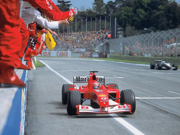 Michael Schumacher, pictured in the Ferrari F2002, raises his fist in victory at the 2002 San Marino Grand Prix.