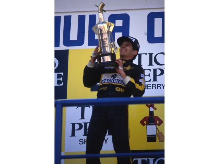 Ayrton Senna lifts the winner's trophy at the 1986 Spanish Grand Prix.