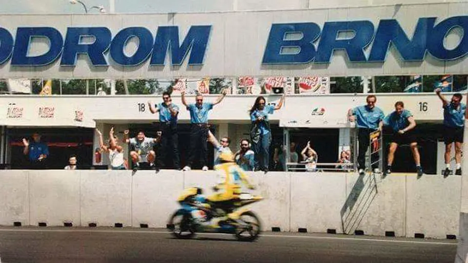 Having just crossed the finish line, Rossi’s teammates cheer from the paddock to celebrate the rookie’s first victory at the 1996 Czech Grand Prix.