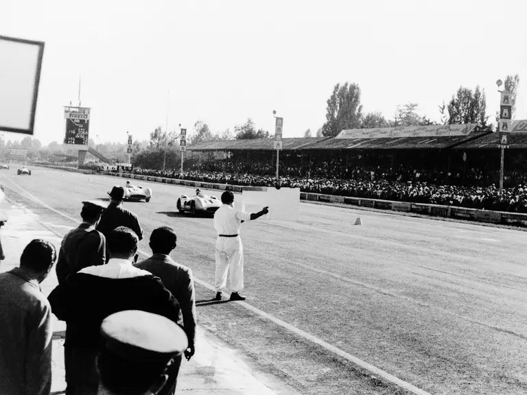  Italian Grand Prix at Monza, 11 September 1955. Eventual winner Juan Manuel Fangio (#18) is followed by Stirling Moss (#16, chassis number 00009/54); both are in Mercedes-Benz Formula One W 196 R racing cars with streamlined bodywork.