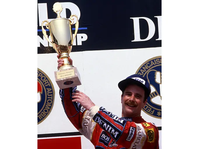 Nigel Mansell is triumphant at Circuit Paul Ricard as he holds aloft the 1st-place trophy from the 1987 French Grand Prix.