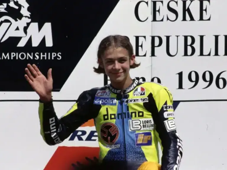 A 17-year-old Valentino Rossi waves on the podium as he awaits his first-place trophy at the 1996 Czech Grand Prix.