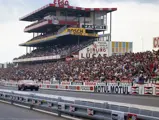 Chassis 12467 thunders along the pit straight, V-12 howl delighting fans in a packed main grandstand.