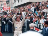 Graham Hill triumphantly raises his 1st-place trophy after having secured victory at the 1969 Monaco Grand Prix.