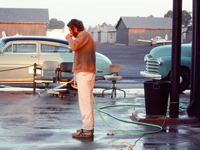 Steve McQueen with his 1952 Hudson Wasp proudly parked outside his hanger at the Santa Paula airport.