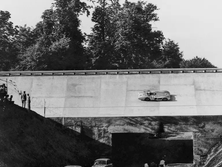 Chassis number 00009/54 in its streamlined configuration, with Stirling Moss (#16) behind the wheel, on the banked Monza circuit during the 1955 Italian Grand Prix.