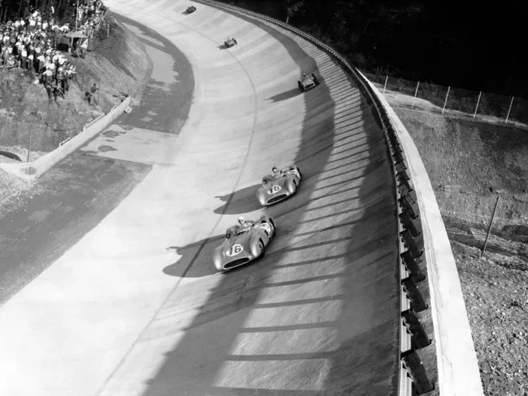 Italian Grand Prix in Monza, 11 September 1955: Stirling Moss (#16, chassis number 00009/54) leads the steep bend ahead of the winner Juan Manuel Fangio (#18), both in Mercedes-Benz W 196 R with streamlined bodywork, followed by Piero Taruffi (#14) in a Mercedes-Benz W 196 R with open-wheel bodywork.