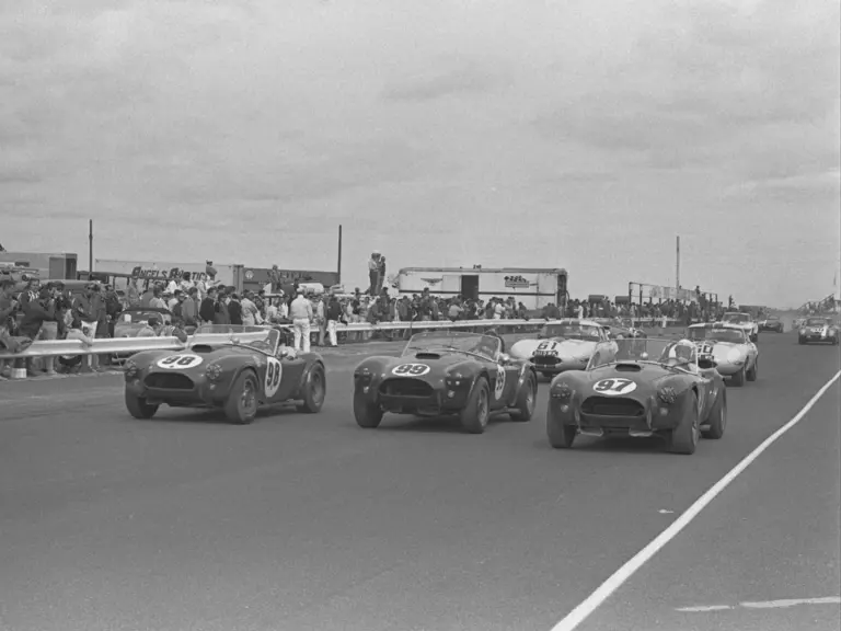 Ken Miles (#98), Dan Gurney (#99), and Bob Holbert (#97) lead the way in the trio of Works Cobras at the Bridgehampton Double 500, September 1963.