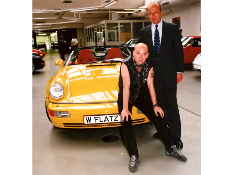 Walter Gnauert, former CFO of Porsche, stands with Flatz as the artist receives his car for the first time in 1994.