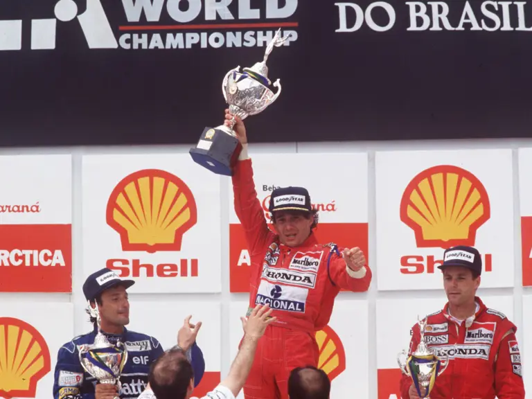 Ayrtona Senna lifts the 1st place trophy following his herculean drive at the 1991 Brazilian Grand Prix.