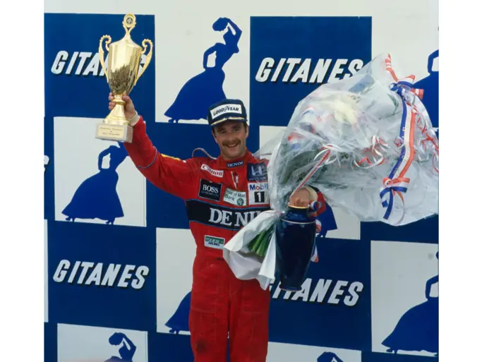 Nigel Mansell holds the 1st-place trophy aloft after winning the 1986 French Grand Prix.