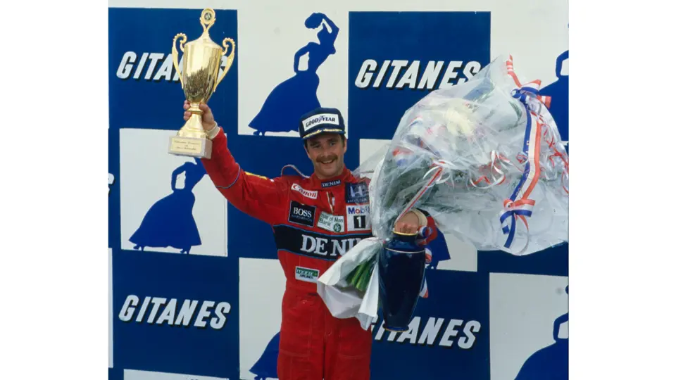 Nigel Mansell holds the 1st-place trophy aloft after winning the 1986 French Grand Prix.