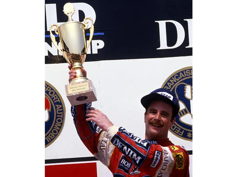 Nigel Mansell is triumphant at Circuit Paul Ricard as he holds aloft the 1st-place trophy from the 1987 French Grand Prix.