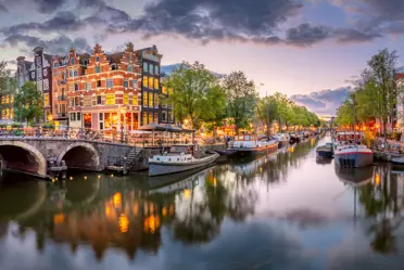 Amsterdam. Panoramic view of the downtown of Amsterdam. Traditional houses and bridges of Amsterdam. A blue evening time and the serene reflection of lights in the water. Long exposure. A European journey to a historic city. Europe, Netherlands, Holland, Amsterdam.