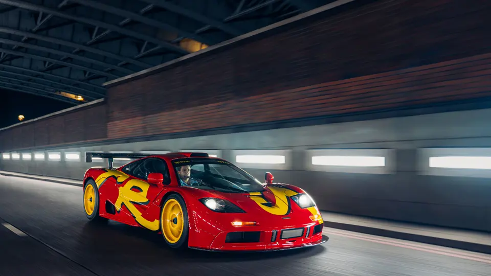 Front three-quarter view of the 1996 McLaren F1 GTR during a nighttime city drive.