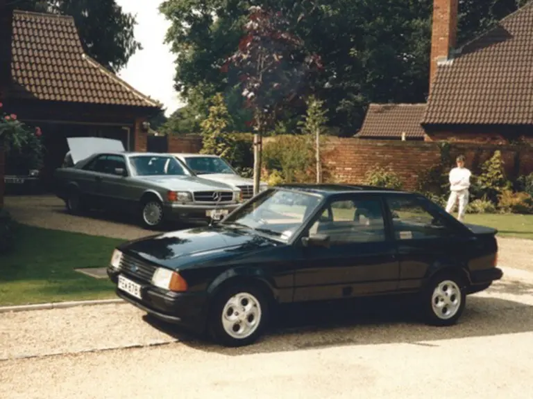 The 190 E 2.3-16 is pictured with other cars at Ayrton Senna’s Esher address. Senna can be seen loading into the boot of the closest Mercedes-Benz.