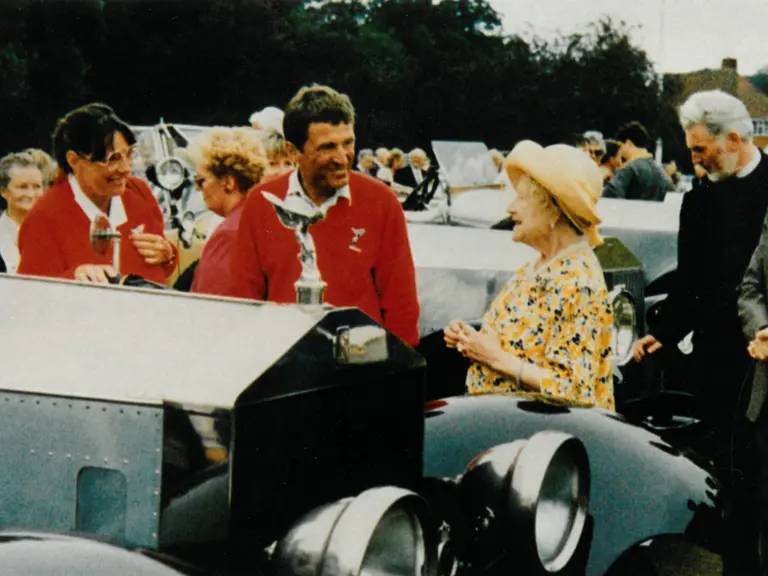 The consigning owner stands with the Silver Ghost in conversation with HRH Queen Elizabeth The Queen Mother, 1991.